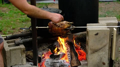 Checking duck for tenderness while meat being roasted on fire pit Video stock 249236401