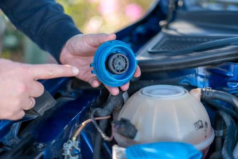 Checking engine coolant reservoir cap during car maintenance Fotos Stock