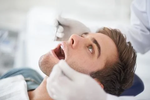 Checking that everything is fine...a young man at the dentist. Stock Photos