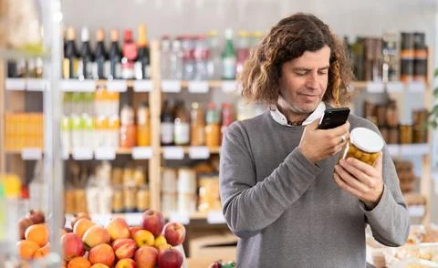 Checking expiration date of canned olives - male shopper scans QR code on label Stock-Fotos