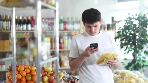 Checking expiration date of chips - guy shopper scans QR code on label of chips Stock Footage 308419036