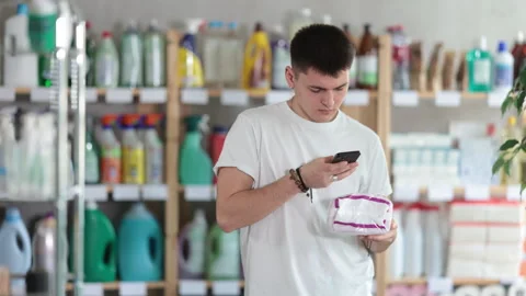 Checking expiration date of feminine pads - male shopper scans QR code on label Stock Footage 312631646