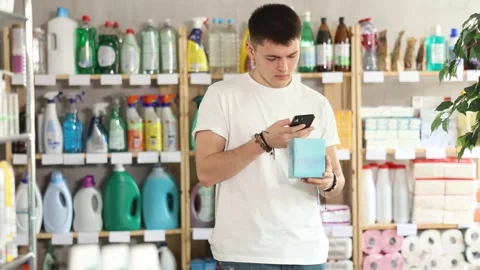 Checking expiration date of feminine pads - male shopper scans QR code on label Stock Footage 323069896