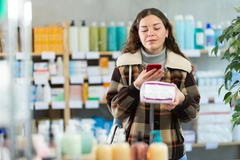 Checking expiration date of feminine pads - female shopper scans QR code on Fotos de archivo