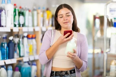 Checking expiration date of liquid hand soap - female shopper scans QR code on Stock Photos