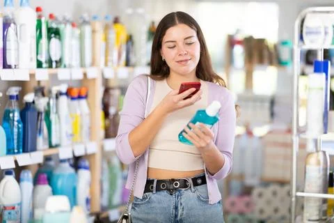 Checking expiration date of liquid hand soap - female shopper scans QR code on Stock Photos