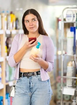 Checking expiration date of liquid hand soap - female shopper scans QR code on Stock Photos