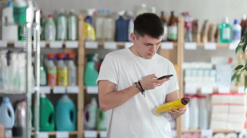 Checking expiration date of parquet liquid - male shopper scans QR code on label Stock Footage 313458221