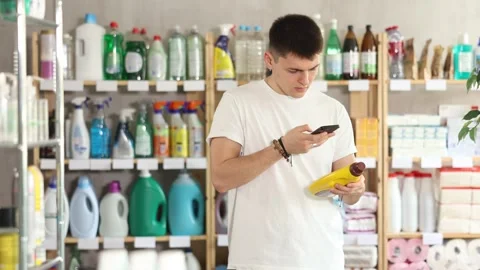 Checking expiration date of parquet liquid - male shopper scans QR code on label Stock Footage 325028226