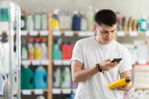 Checking expiration date of parquet liquid - male shopper scans QR code on label Stock Photos