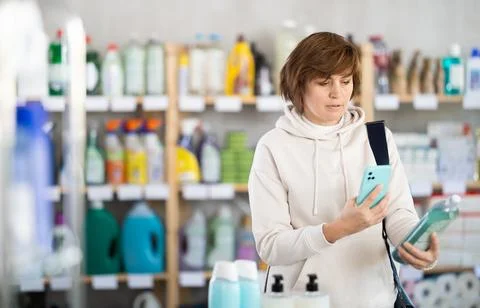 Checking expiration date of shampoo or shower gel - female shopper scans QR code Stock-Fotos