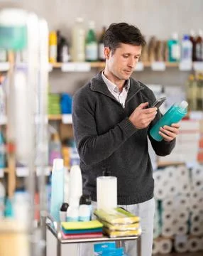 Checking expiration date of shampoo or shower gel - male shopper scans QR code Stock-Fotos