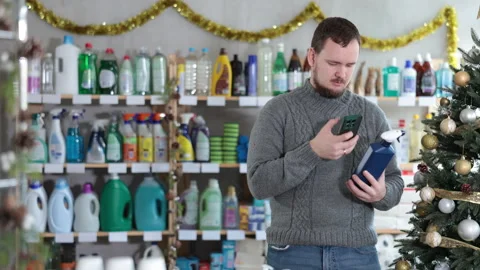 Checking expiration date of spray glass cleaner for windows - male shopper scans Stock Footage 308604059