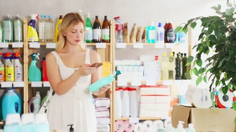 Checking expiration date of spray glass cleaner for windows - female shopper Stock Footage 309540025