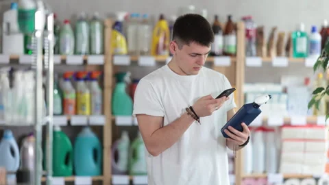 Checking expiration date of spray glass cleaner for windows - male shopper scans Stock Footage 315552163