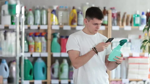 Checking expiration date of spray glass cleaner for windows - male shopper scans Stock Footage 328139771