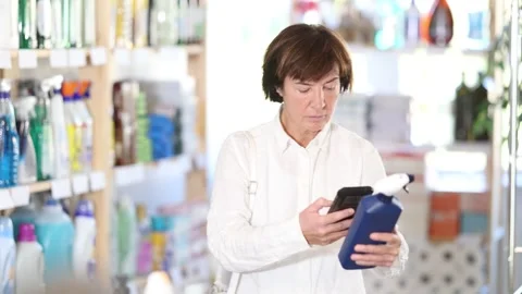 Checking expiration date of spray glass cleaner - male shopper scans QR code on Stock Footage 341526014