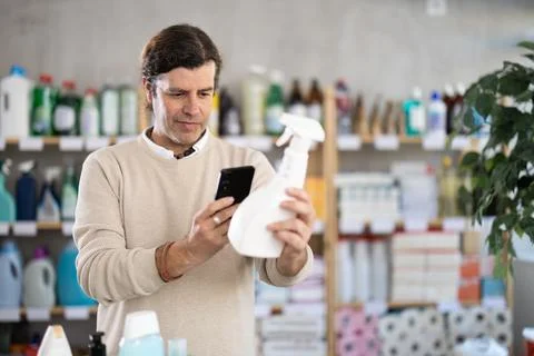 Checking expiration date of spray glass cleaner for windows - male shopper scans Stock Photos