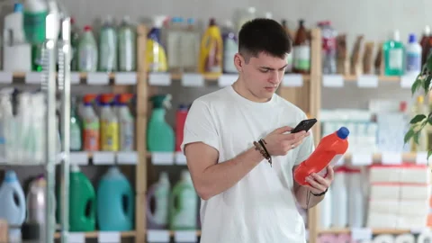 Checking expiration date of unclogging liquid - male shopper scans QR code on Stock Footage 316581039