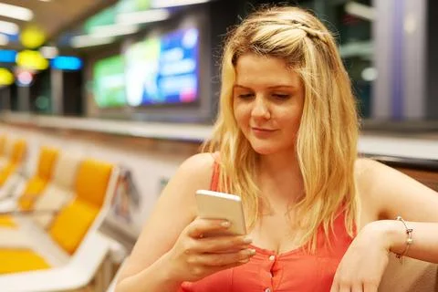 Checking up on her flight status. a young woman using a cellphone while sitting Fotos de archivo