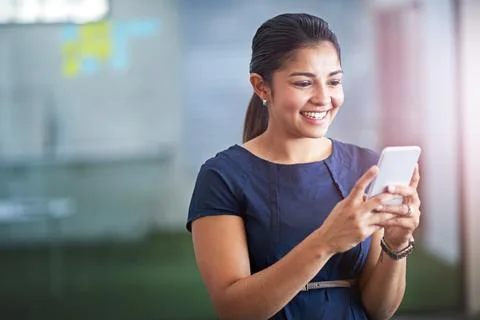 Checking her inbox. an attractive young businesswoman using her cellphone in the Stock Photos