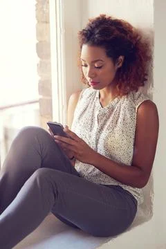 Checking her schedule for today. a young woman using her cellphone while sitting 스톡 사진