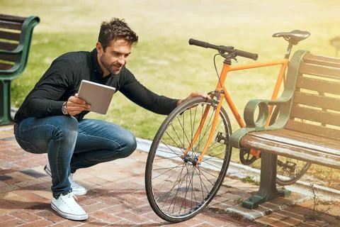 Checking on his bicycle. Full length shot of a handsome young man using his 写真素材