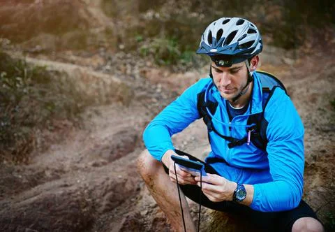 Checking his location using the GPS on his smartphone. Shot of a cyclist usin Fotos de archivo