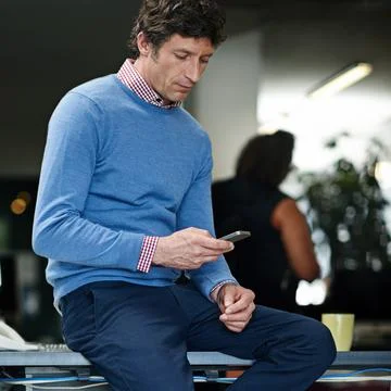 Checking his messages. a businessman using his cellphone at work in an office. Fotos de archivo