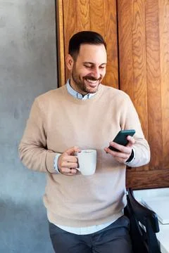 Checking his messages over coffee. Man using a smart phone while drinking coffee 스톡 사진