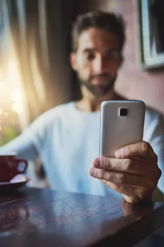 Checking his messages. a young man using his cellphone in a coffee shop. Foto stock