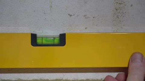 Checking level with a yellow  aluminium builders glass bubble spirit level  Vidéo 163102314