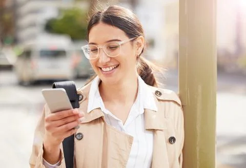 Checking the local hotspots. Shot of a young woman using a smartphone while o Stock Photos