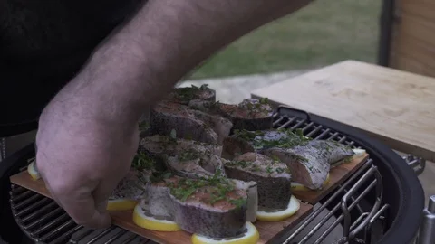 Checking on marinated chunks of salmon grilling on a wooden boards Stock-Footage 111512944