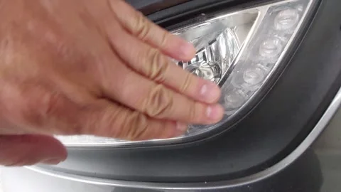 Checking a modern car fog light and daytime running LED lamp with hand close up Stock Footage 335395271