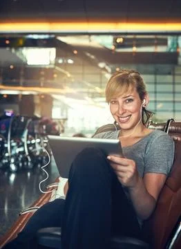 Checking my flight plan. a young woman using a tablet in an airport. Stock Photos