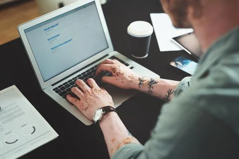 Checking for new job posts. a young businessman using a laptop in an office at Stock Photos