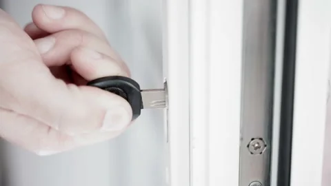Checking the operation of the lock in a plastic door. A hand inserts a 库存影片 239601289