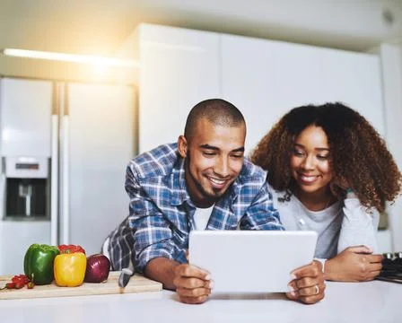 Checking out different recipes online. a young couple using a tablet together at Fotos de archivo