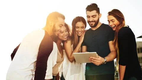 Checking out new apps together. young friends using a tablet outside. Foto stock