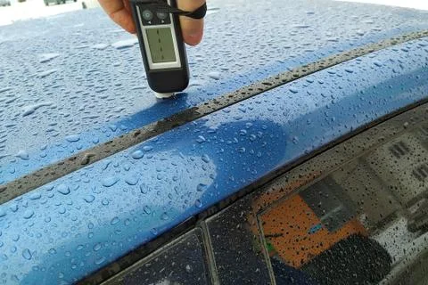 Checking the paint thickness of a blue car in the rain Stock Photos