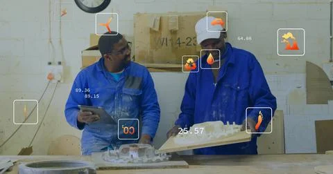 Checking plaster molds, two techs in blue work jackets handling tablet on wooden Stock Photos