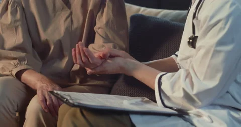 Checking pulse. Close-up female doctor in lab coat examining older patient at Stock Footage 162321182