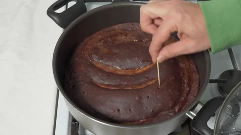 Checking the readiness of the cake with cocoa and chocolate with fried bananas Stock Footage 232624189