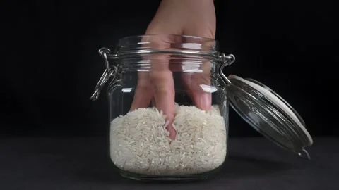Checking rice in glass jar by hand isolated black background Stock Footage 278017923