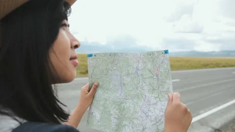 Checking road and way by paper map, woman tourist holds it in her hands, looks Video stock 140384123