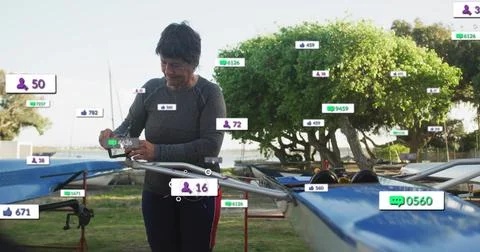 Checking senior in athletic top viewing phone near rigging at launch, blue shell Stock Photos