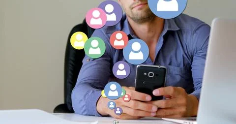 Checking smartphone office worker wearing blue shirt at desk with laptop and Foto stock