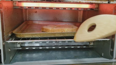 Checking with spatula slice of bread topped with butter being broiled 스톡 동영상 105551230
