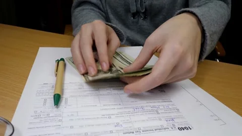 Checking tax forms and using a calculator and pen filling US 1040 tax form .. Stock Footage 272783335